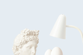 A statue of a man watching eggs under a lamp