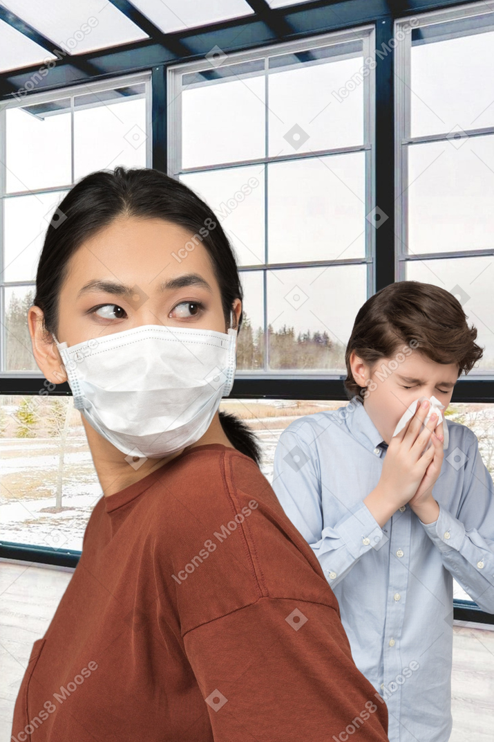 A woman wearing a face mask and a boy sneezing