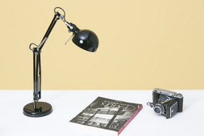 Lámpara de escritorio, cámara vintage y libro
