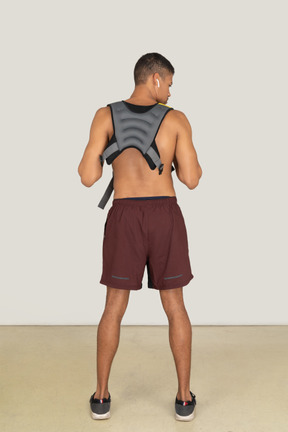 Back view of athletic guy wearing weighted vest