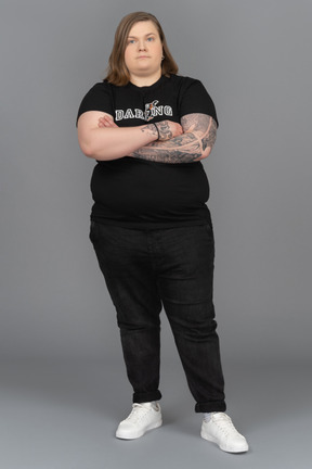 Very serious plump woman standing with her arms crossed