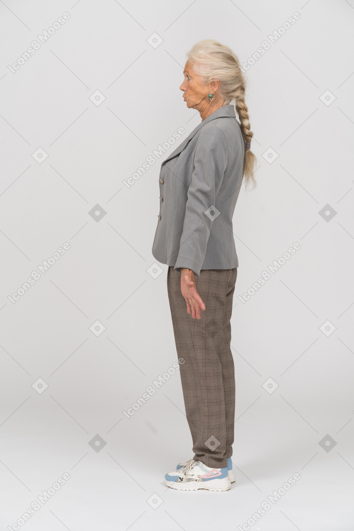Emotional old woman in grey jacket standing in profile