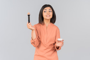 Indian woman holding powder brush and face powder