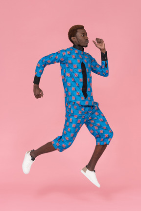 Hombre negro en pijama azul saltando sobre fondo rosa