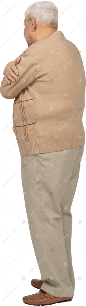 Side view of a happy old man in casual clothes hugging himself