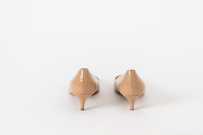 A back shot of a pair of beige lacquer court shoes