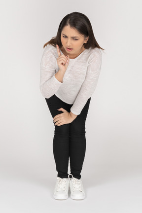 Front view of a young indian female in casual clothes leaning on arms & bending knees