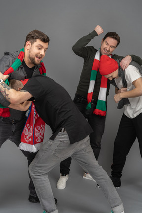 Close-up of four fighting male football fans