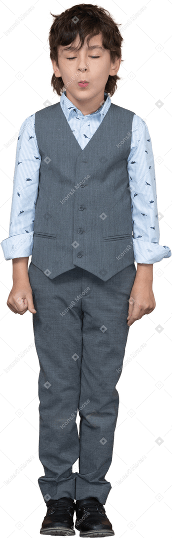 一个穿着灰色西装、闭着眼睛站着的小男孩的前视图