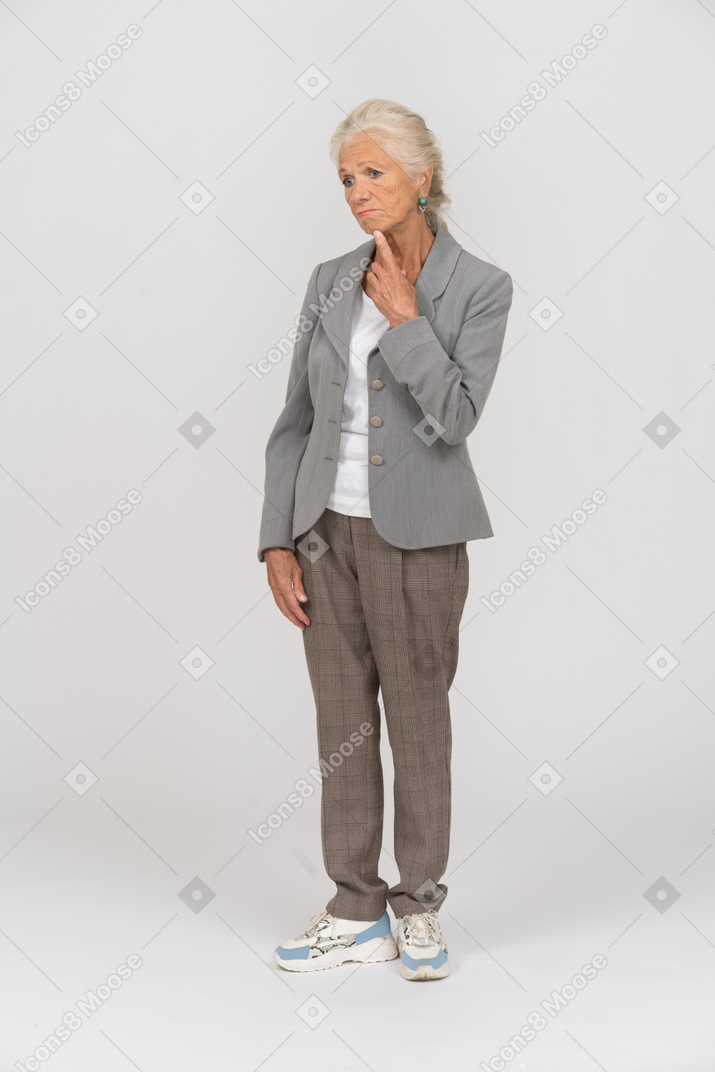 Front view of a thoughtful old lady in suit touching her chin
