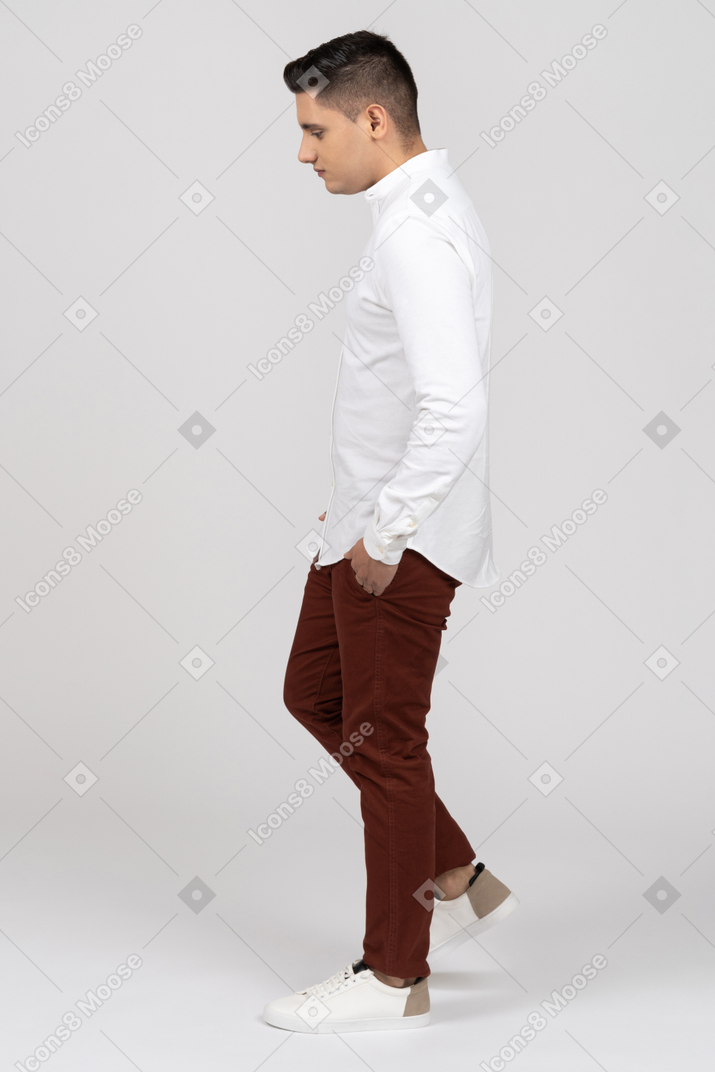 Vista lateral de um jovem latino avançando com as mãos nos bolsos