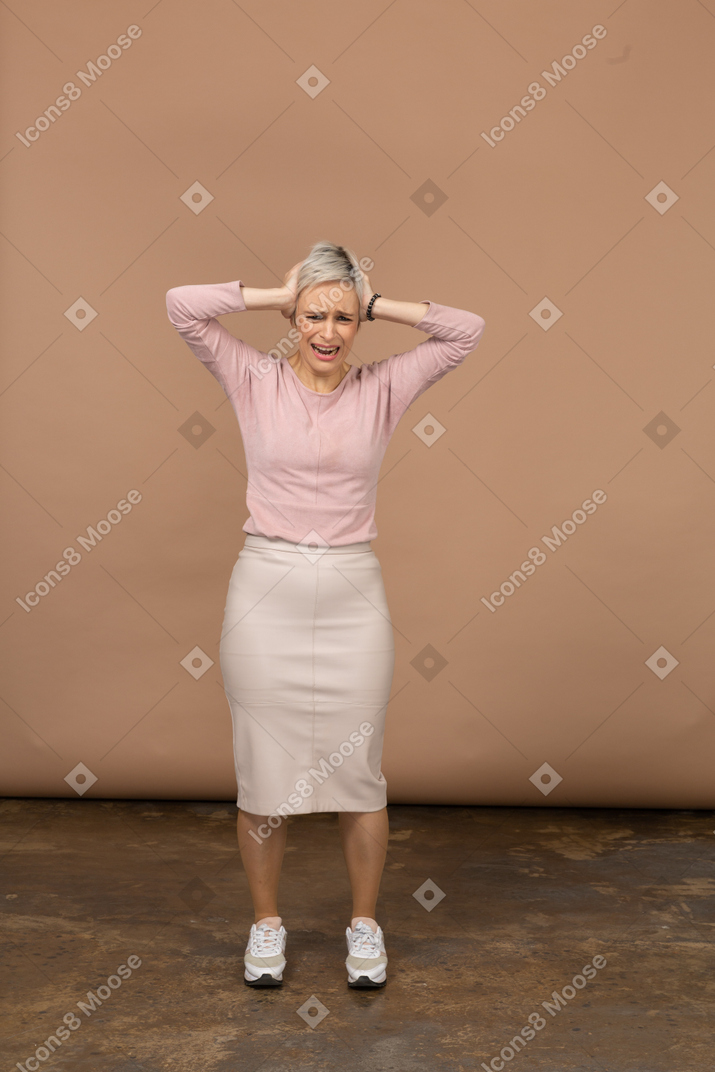 一个穿着休闲服、双手放在头上的情绪化女人的正面图