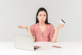 Giovane donna asiatica sembrante triste che fa spesa online