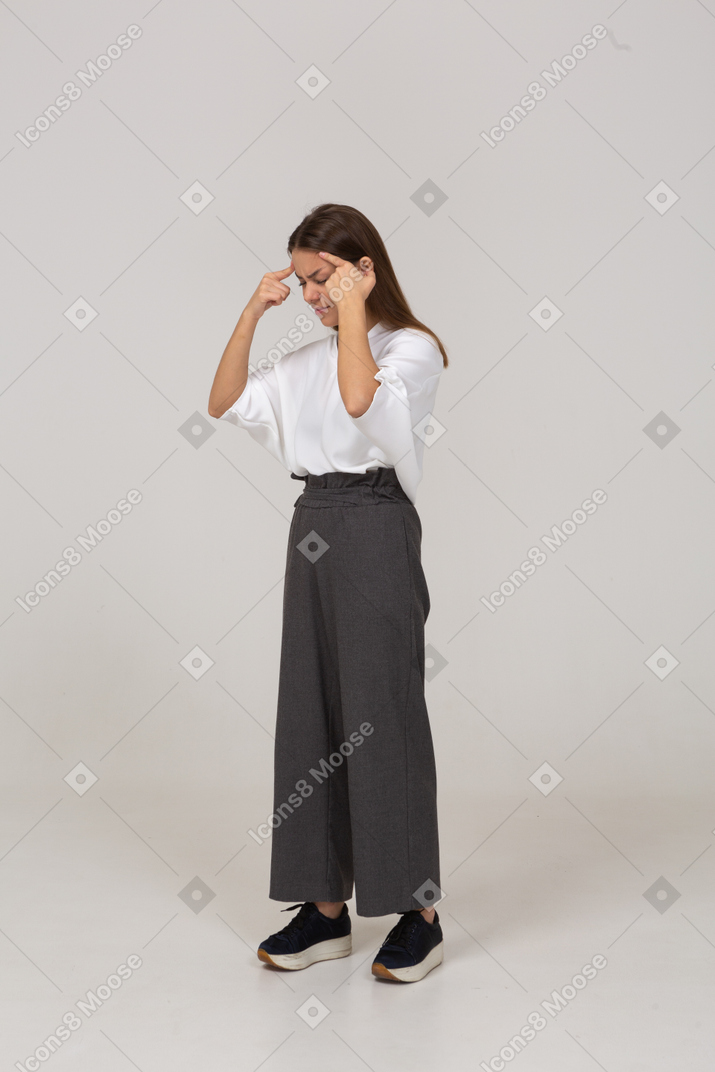 Three-quarter view of a young lady in office clothing touching head