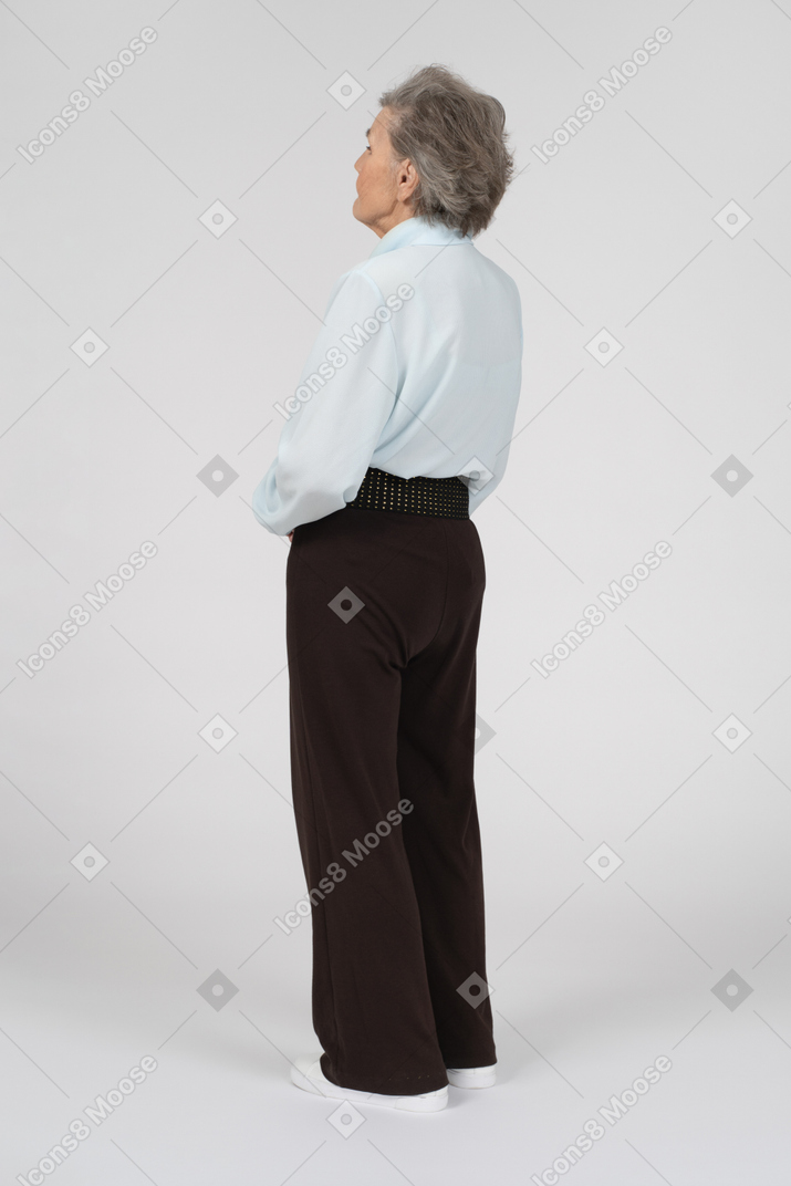 Three-quarter back view of an old woman standing straight