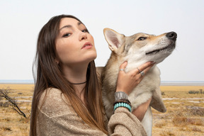 A woman is holding a dog in a field