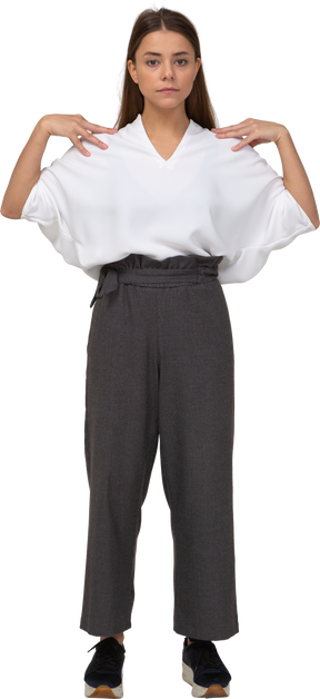 Front view of a young lady in office clothing touching her shoulders