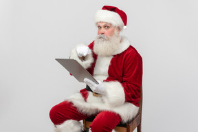 Санта-клаус, указывая на папку и выглядит потерянным