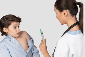 Scared boy looking at doctor's syringe