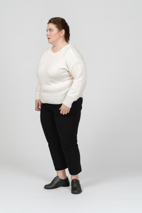 Mulher de tamanho grande em suéter branco de pé de perfil