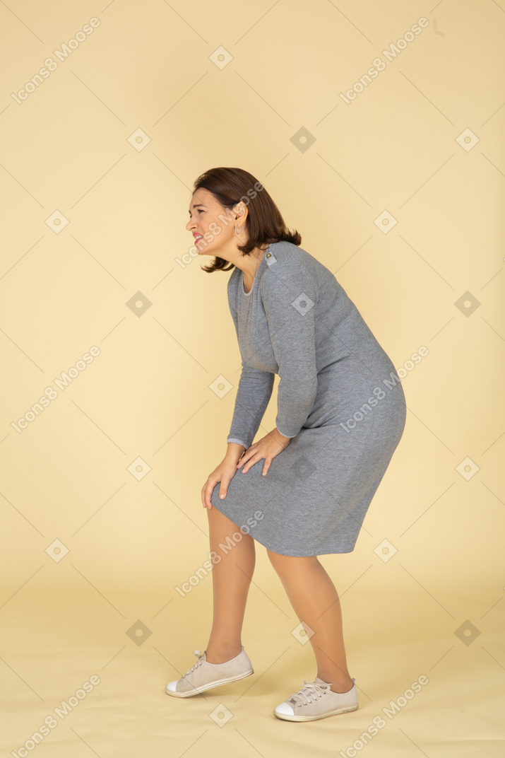 Vista lateral, de, un, mujer, en, vestido gris, tocar la rodilla