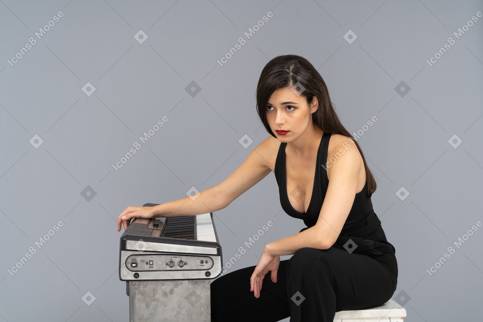 Full-length of a sad young female sitting by the piano while looking aside