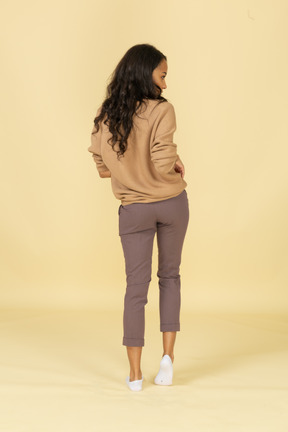 Back view of a dark-skinned young female rolling up her pullover