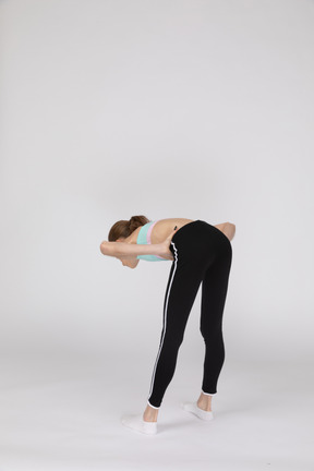 Side view of a teen girl in sportswear squatting and putting hands on hips