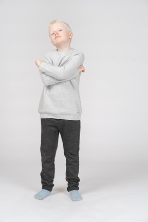 Front view of a cool kid boy raising head and crossing hands