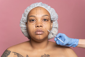 Mulher tatuada, recebendo injeção de botox
