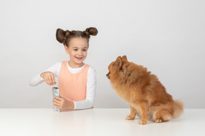 Kind mädchen ein päckchen hundefestlichkeit für ihr spitz haustier öffnen