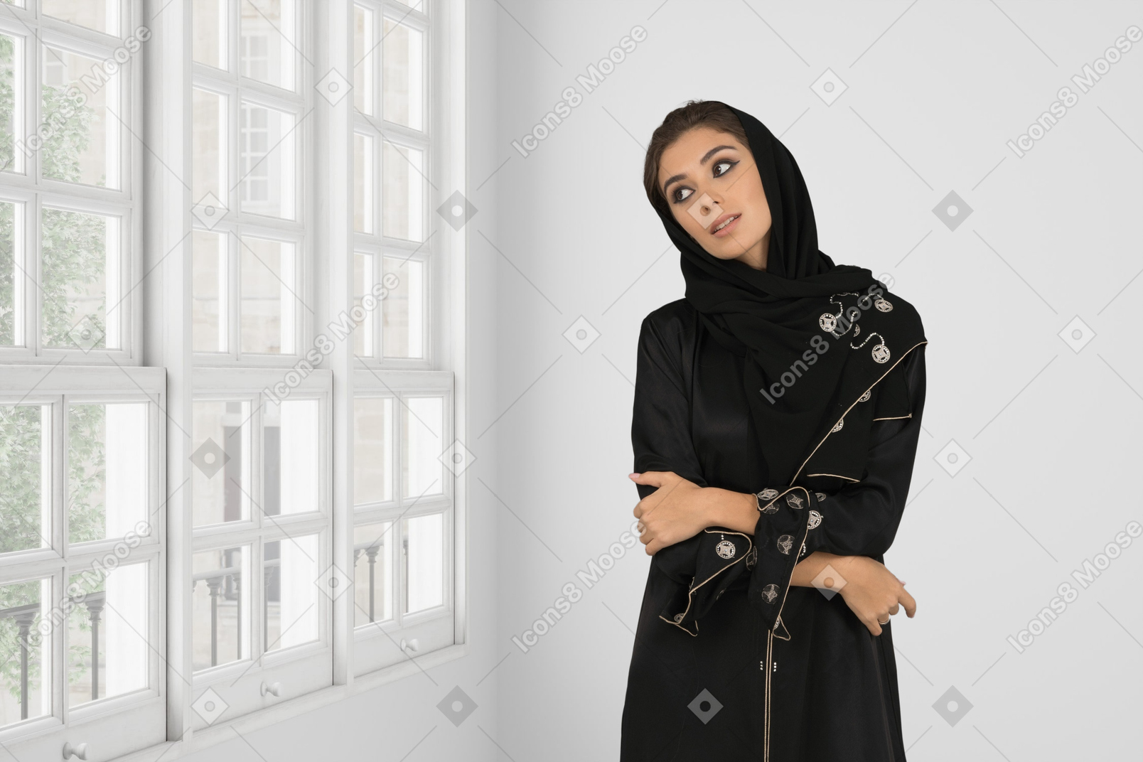 A woman in a black sweater and long skirt standing in front of a window