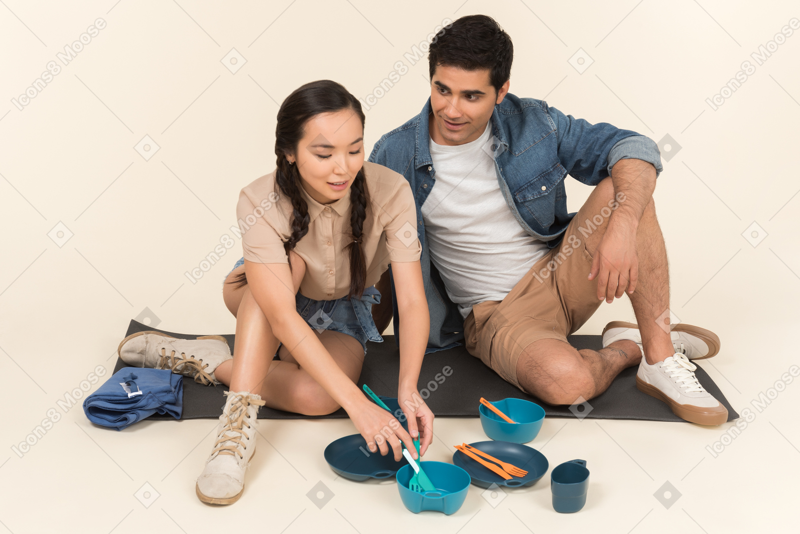 Jovem casal interracial sentado no karimat e apontando