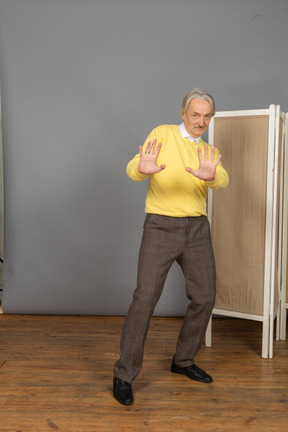 Front view of a confused old man outstretching his hands