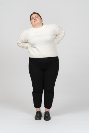 Mulher plus size com roupas casuais, sofrendo de dores na parte inferior das costas