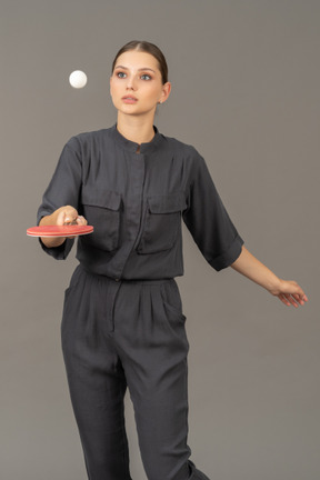 Front view of young woman in a jumpsuit playing table tennis