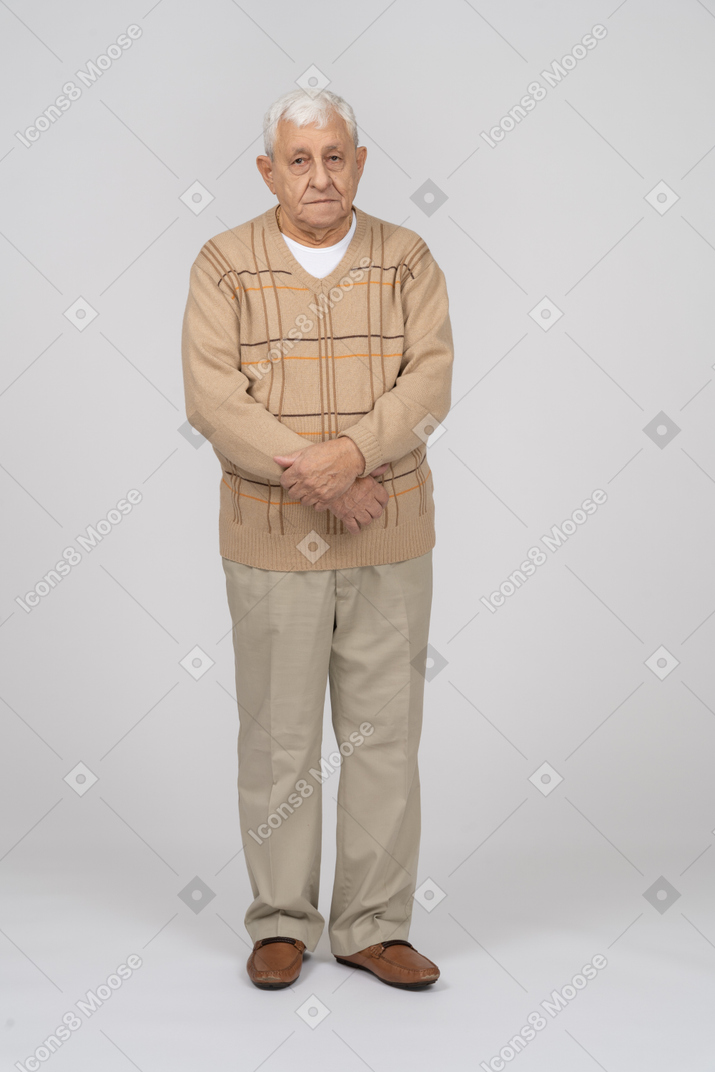 Vorderansicht eines alten mannes in freizeitkleidung, der mit gekreuzten händen steht