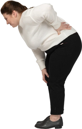 Plus size woman in white sweater suffering from pain in lower back