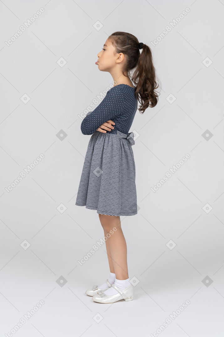Vista lateral de una niña doblando las manos y haciendo pucheros fuertemente