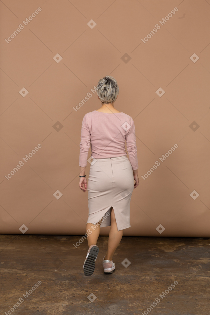 歩くカジュアルな服を着た女性の背面図