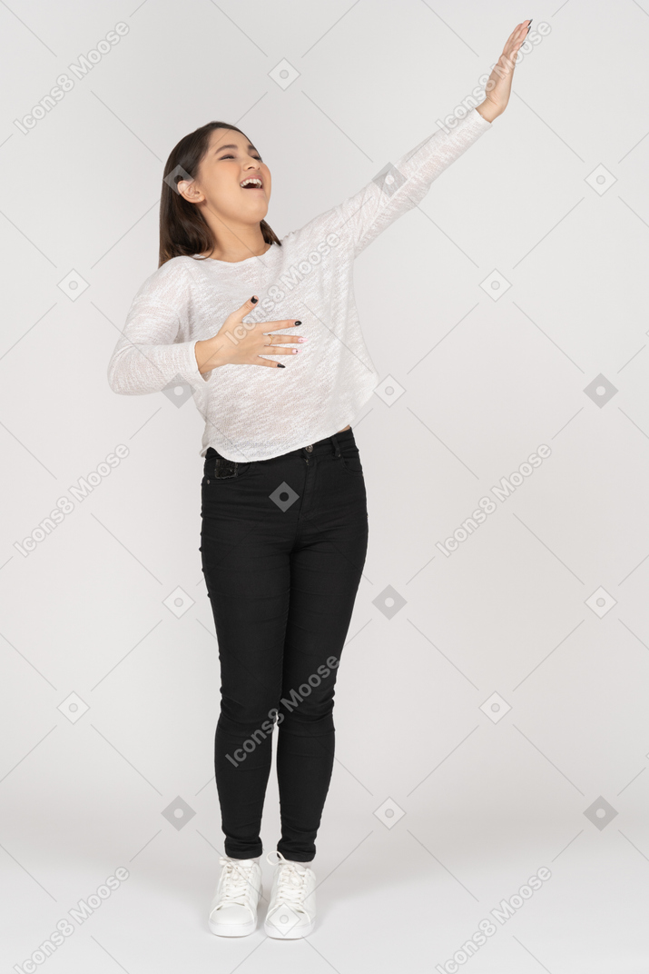 一位穿着休闲服的唱歌的年轻印度女性伸出手臂的前视图