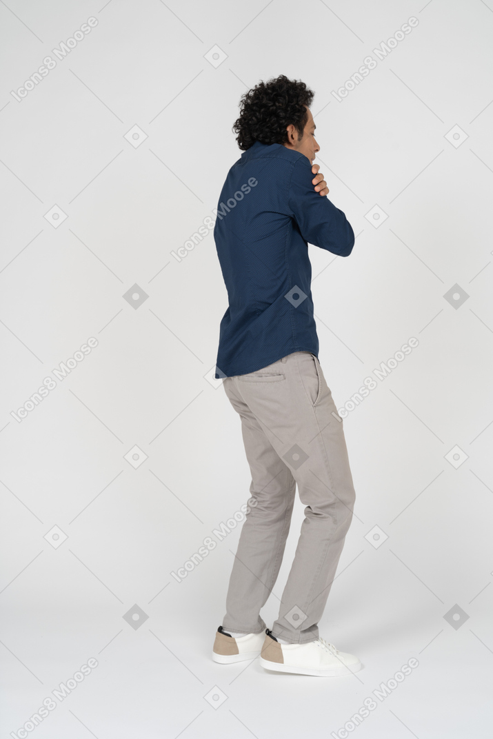 Side view of a man in casual clothes hugging himself