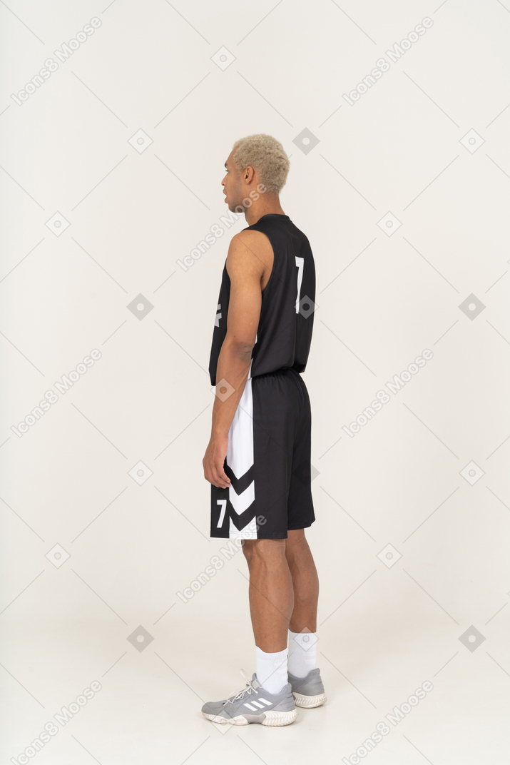 Vista posteriore di tre quarti di un giovane giocatore di basket ansimante