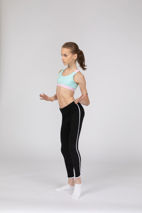 Three-quarter view of a teen girl in sportswear dancing while gesticulating