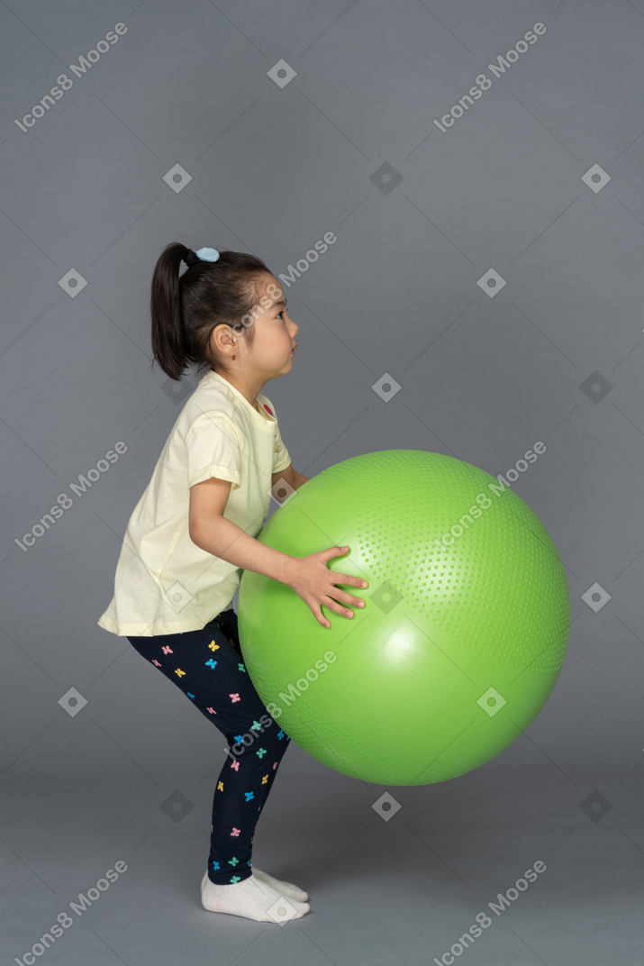 Little girl holding a green fitball