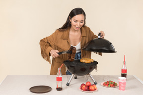 Young asian woman holding grill opened and preparing bbq