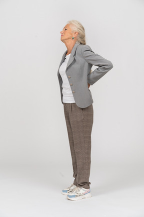 Side view of an old lady in suit suffering from pain in back
