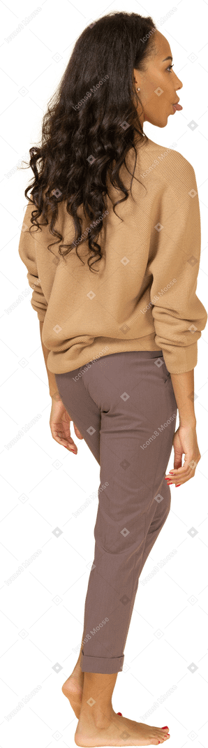 Vista traseira de uma jovem mulher com roupas casuais, mostrando a língua