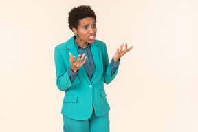 Black woman with a short haircut, wearing all blue, standing against a plain pastel background, looking emotional