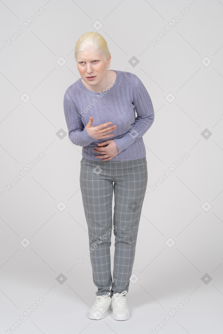 Молодая женщина наклоняется с больным желудком
